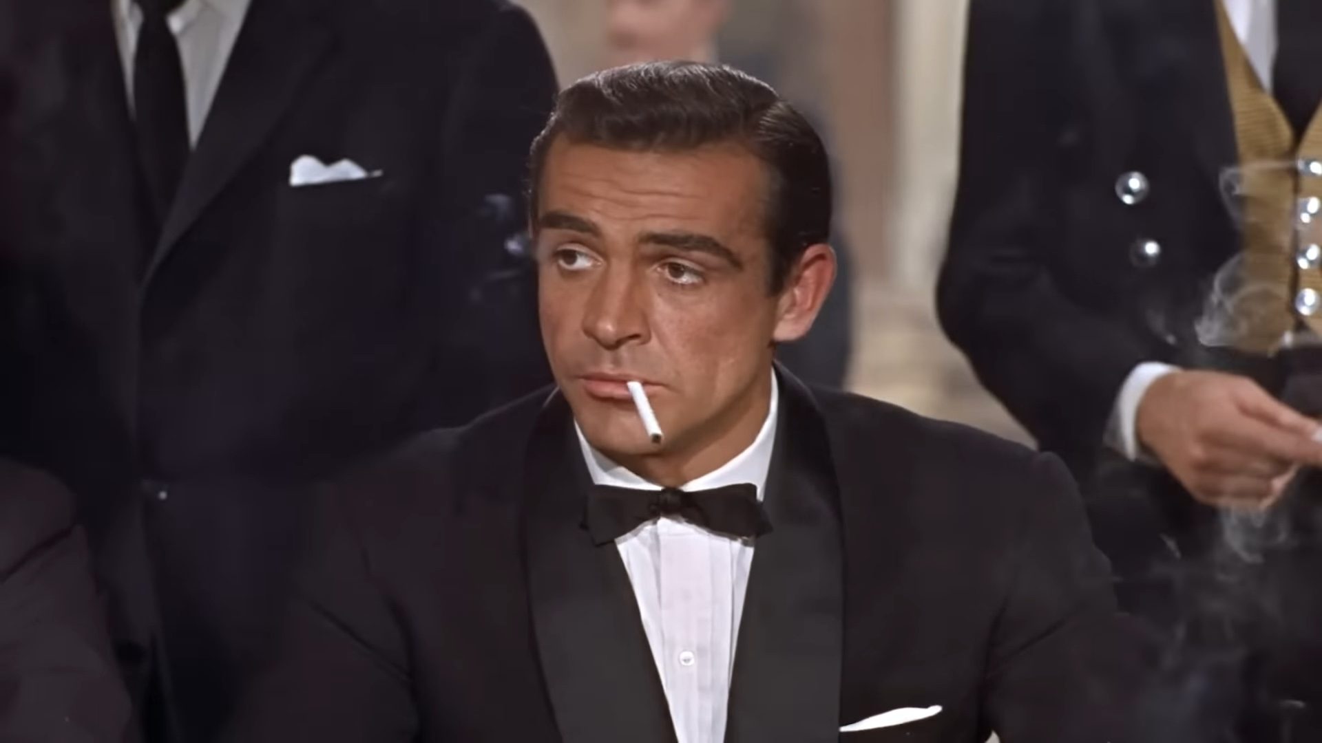 James Bond in "Dr. No" smoking a cigarette in a tuxedo.