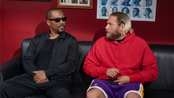 Eddie Murphy and Jonah Hill as Akbar and Ezra sitting side by side and staring at each other in the 2023 movie You People.