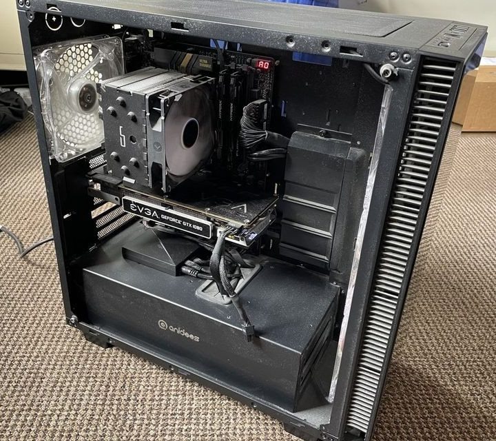 A gaming PC running with its fan spinning and side panel removed.