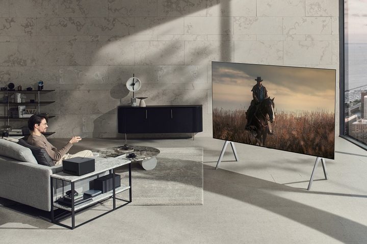 LG's wireless Signature OLED M TV seen on a set of legs in the middle of a room.