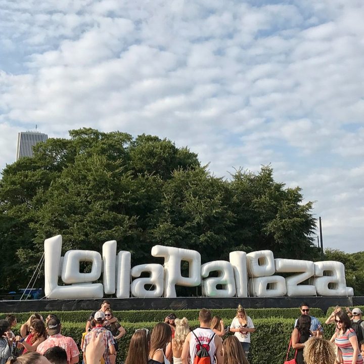 People stand in front of the Lollapalooza Chicago Welcome Sign.