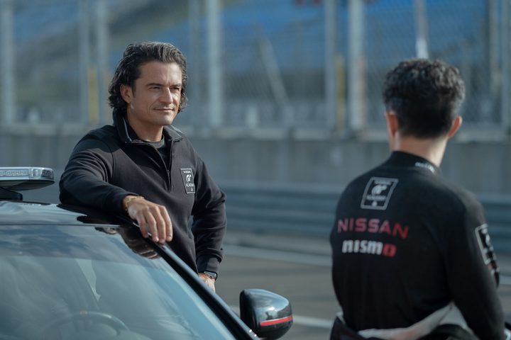 Orlando Bloom leans on a car in Gran Turismo.