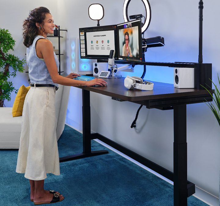 A woman stands at the Corsair Platform:6 desk as she participates in a video call.