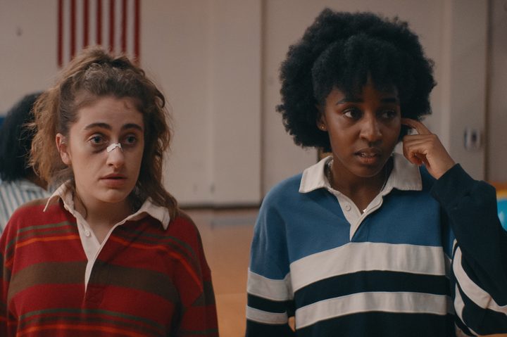 Rachel Sennott and Ayo Edebiri stand in a school gym together in Bottoms.