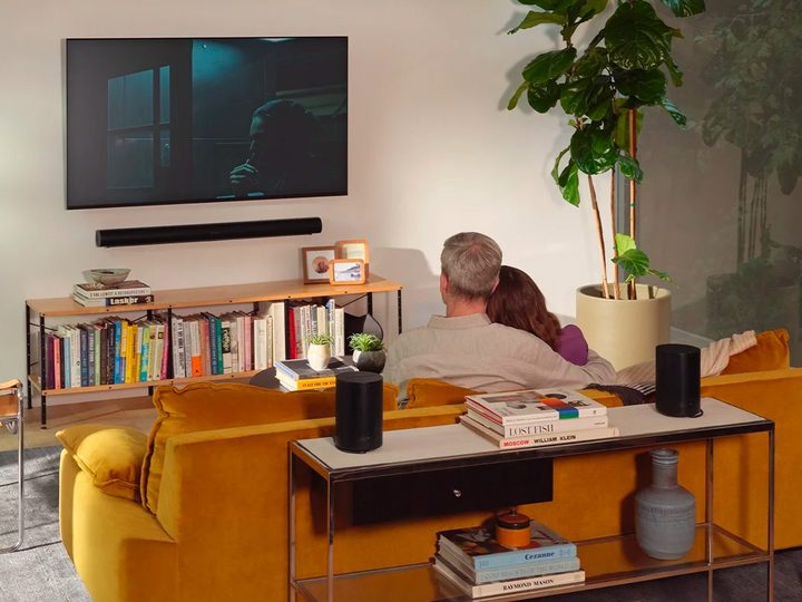 A couple watches TV with a Sonos surround set with Arc wireless soundbar set up.