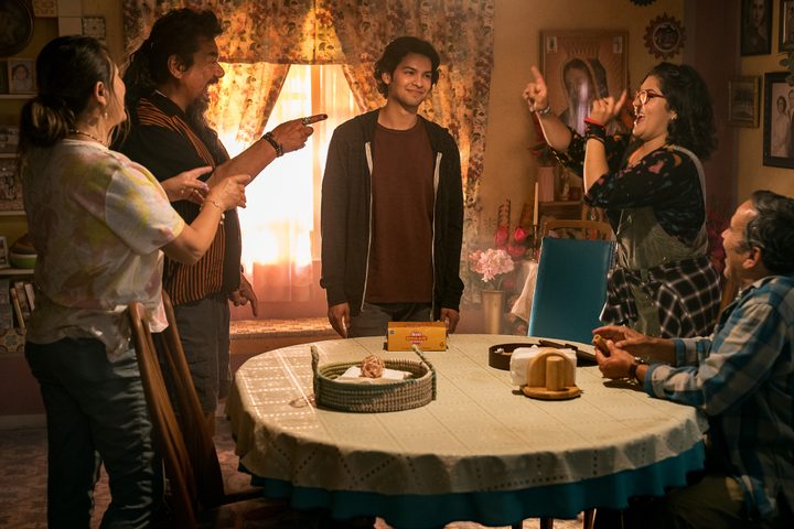 The Reyes family stands around a dinner table together in Blue Beetle.