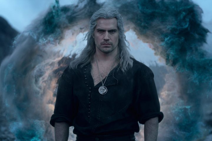 Henry Cavill walks in front of a smoke explosion in The Witcher.