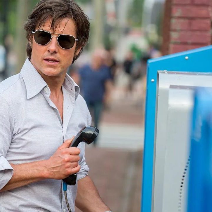 Tom Cruise as Barry Seal holding a public phone and looking to his right in 2017's American Made.