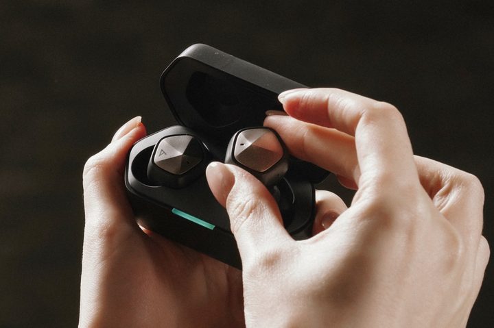 Astell&Kern UW100 MK II wireless earbuds held in hand.
