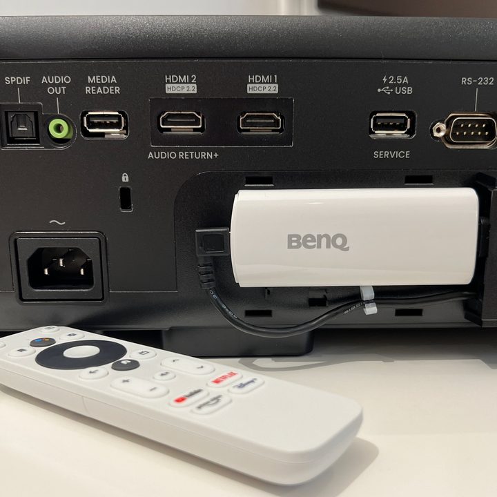 The back of the BenQ HT4550i 4K projector showing the installation of the Android TV dongle.
