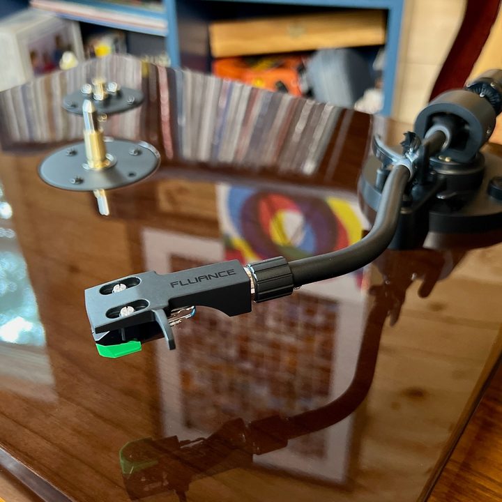The walnut plinth and s-shaped tonearm and cartridge of the Fluance RT81+ turntable.