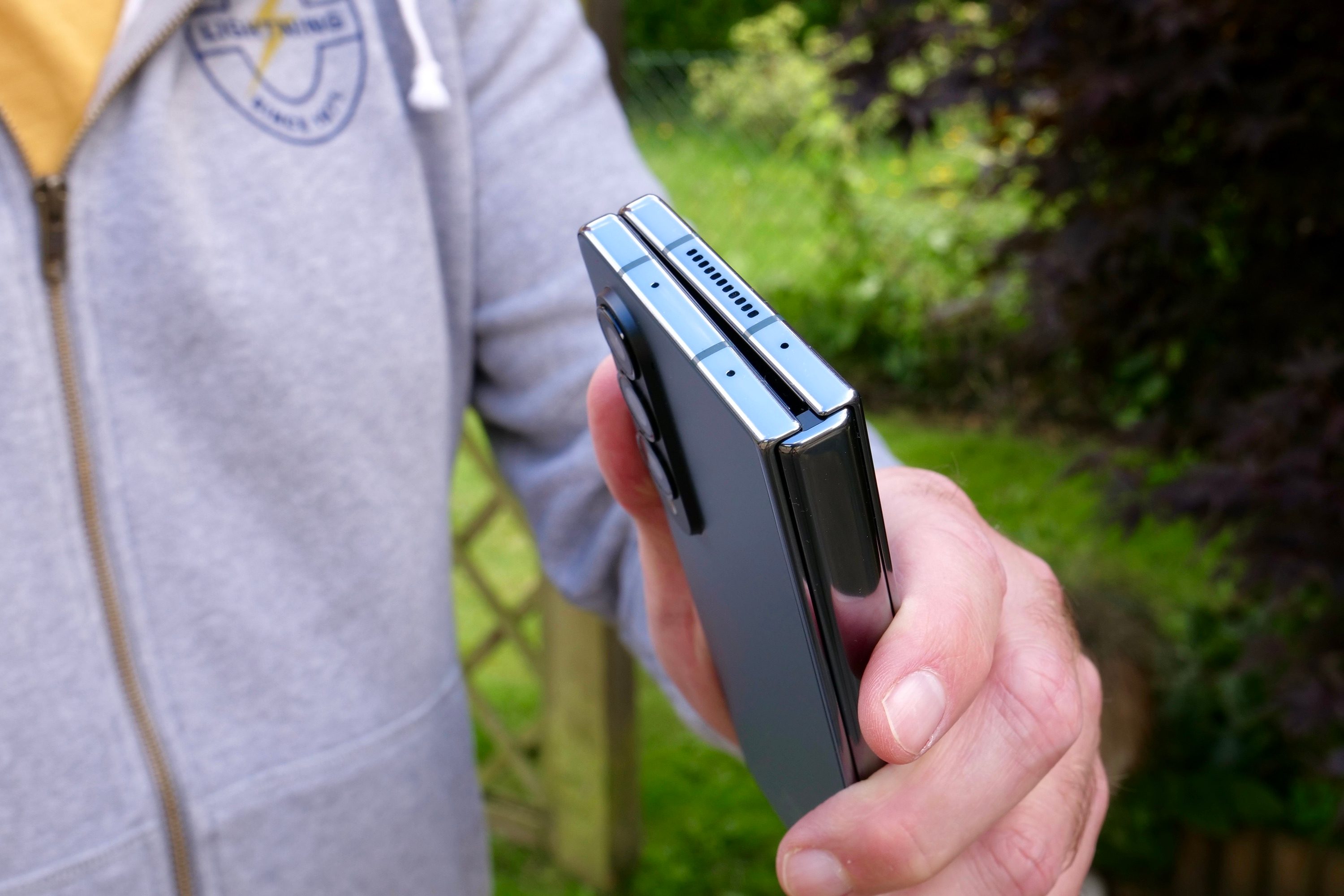 A person holding the Samsung Galaxy Z Fold 4, showing the top of the hinge.