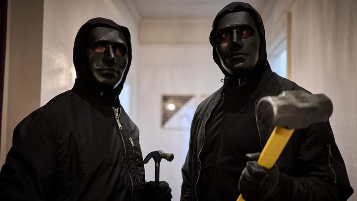 Two men wearing black hoodies and masked, one wielding a mallet and the other a hammer in a scene from Gangs of London.