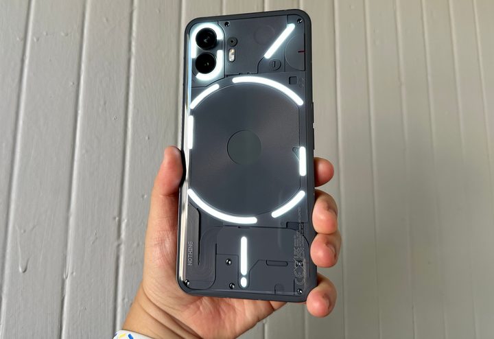 Nothing Phone 2 held in hand with the Glyph Flashlight on.