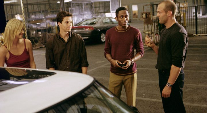Four people stand around a car in The Italian Job.