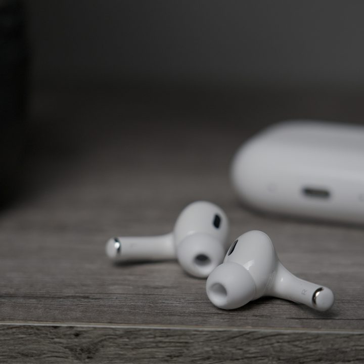 The Apple AirPods Pro 2 with USB-C and MagSafe buds on a table with case in the background.