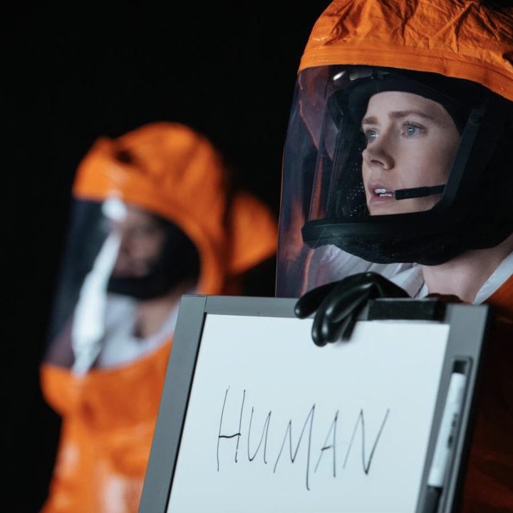 Amy Adams holds up a whiteboard sign in Arrival.