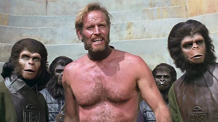 Charlton Heston as George Taylor standing with a group of apes in 1968's Planet of the Apes.