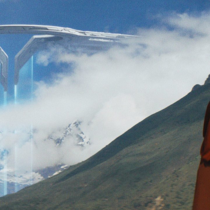 A monk-like android sees a hostile drone shift emerge from the clouds in the distance.