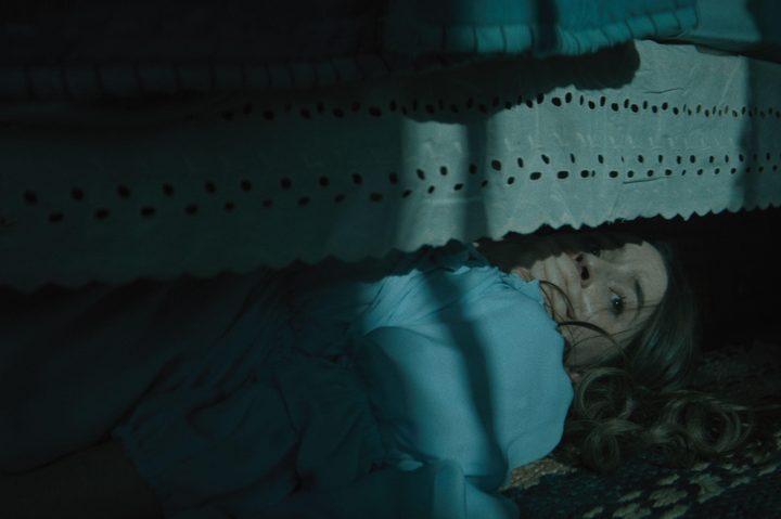 Kaitlyn Dever hides under a bed in No One Will Save You.