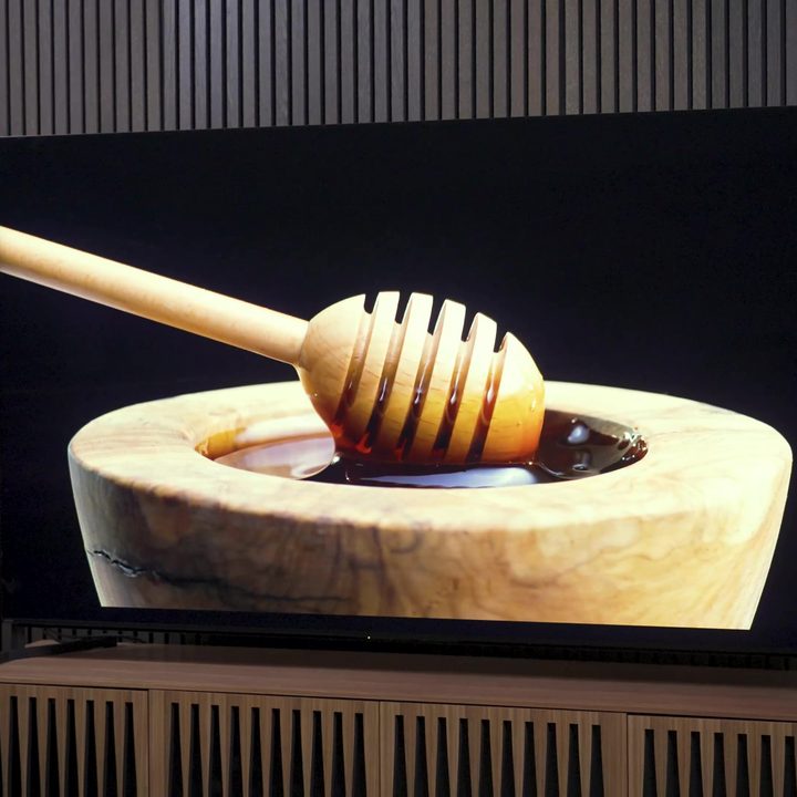 A still image of a honey drizzler in a vessel of honey on a Sony Bravia X95L.