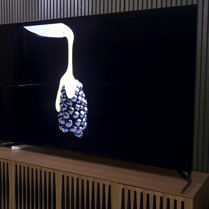 Cream is poured over a single blackberry shown on a Sony X95L mini-LED TV.