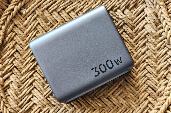 Ugreen 300W GaN fast charger with four USB-C and one USB-A port on top of cane bamboo furniture.
