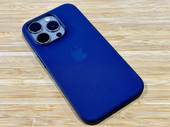 Pacific Blue FineWoven case on a Natural Titanium iPhone 15 Pro on a wooden table.