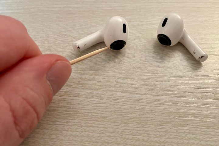Cleaning around AirPods Pro grilles with toothpick.