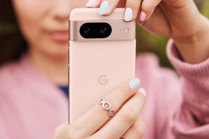 Someone holding up the pink Google Pixel 8, while also wearing a pink shirt.