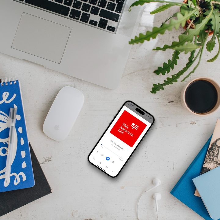 Google Podcasts app being showing on iPhone on a desk.