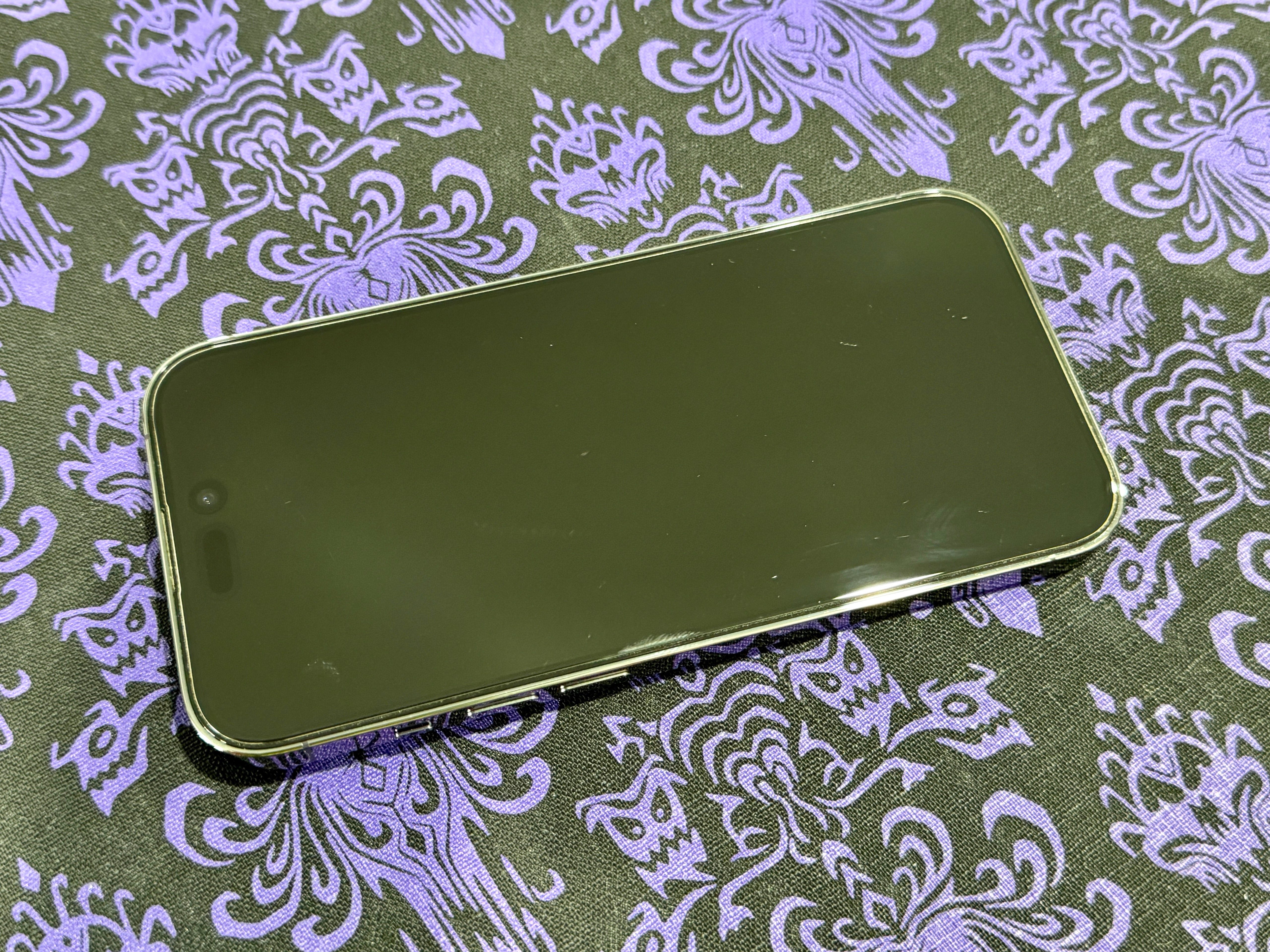Scratches are seen on a screen protector on Christine's iPhone 14 Pro.