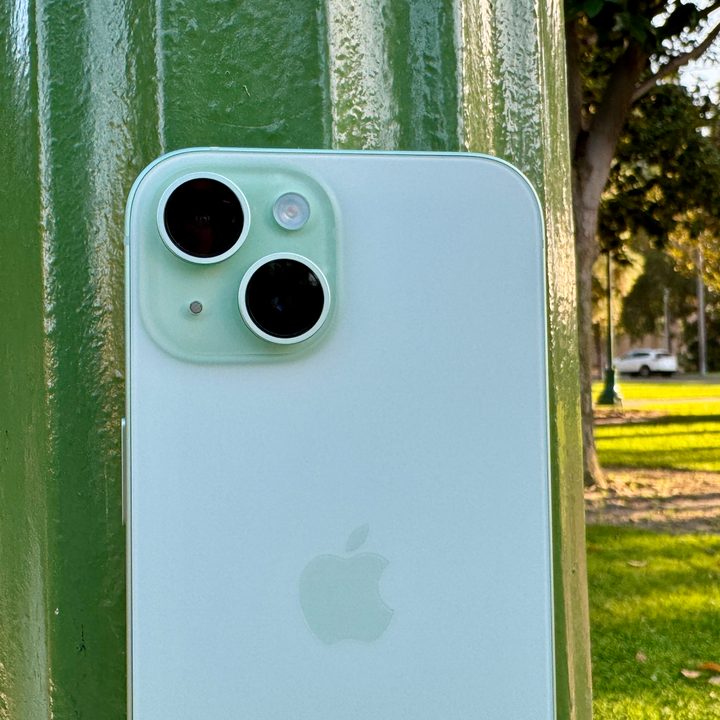 A green iPhone 15 leaning on lamp post.