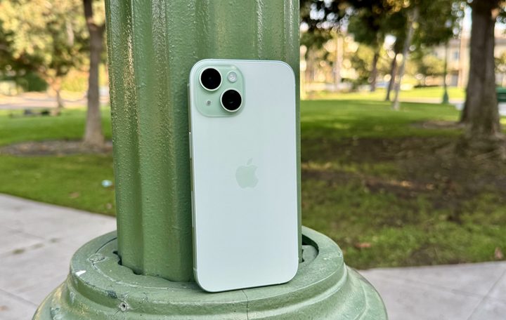 A green iPhone 15 leaning on a lamp post.