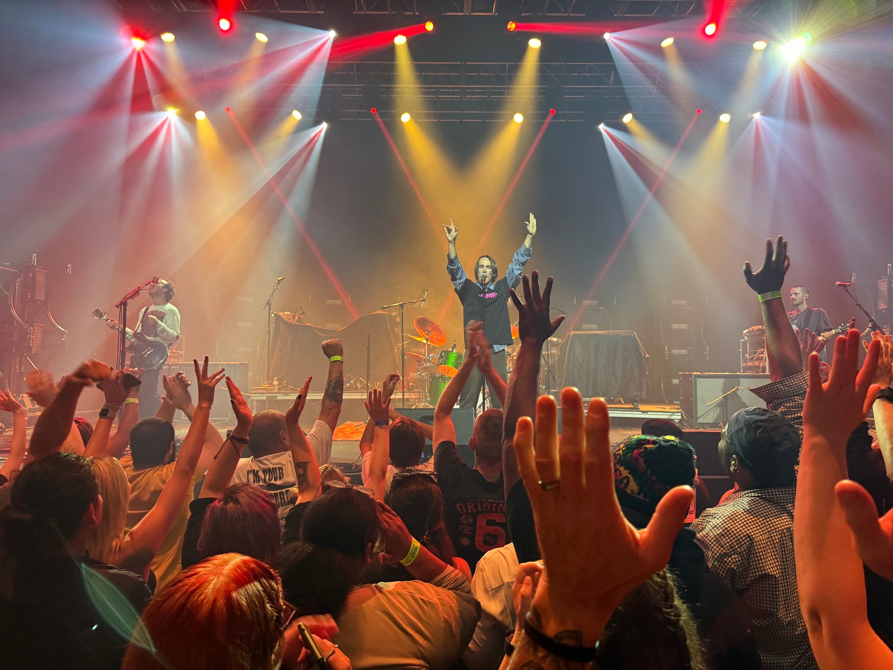 Photo from the iPhone 15 Pro Max main camera of a concert with red and yellow lights.