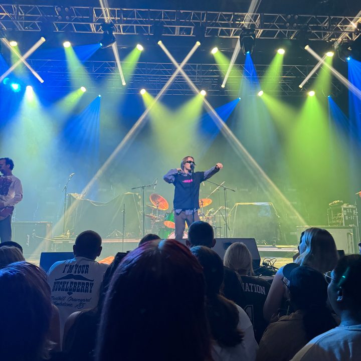 Photo from the iPhone 15 Pro Max main camera of a concert with green and blue lights.