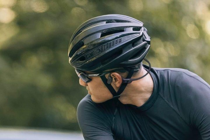 A person wearing Shokz OpenRun bone conduction headphones on a bike.