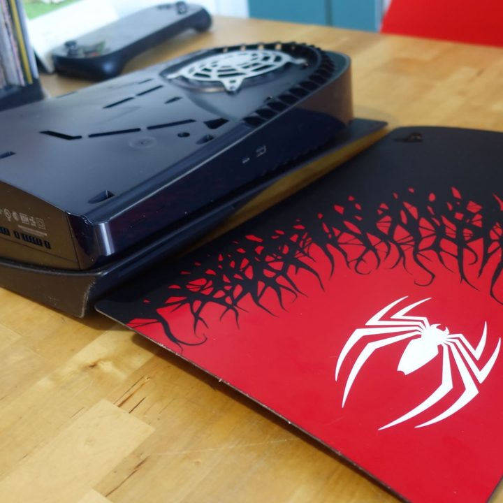 A Spider-Man themed PS5 faceplate sits dethatched from the console.