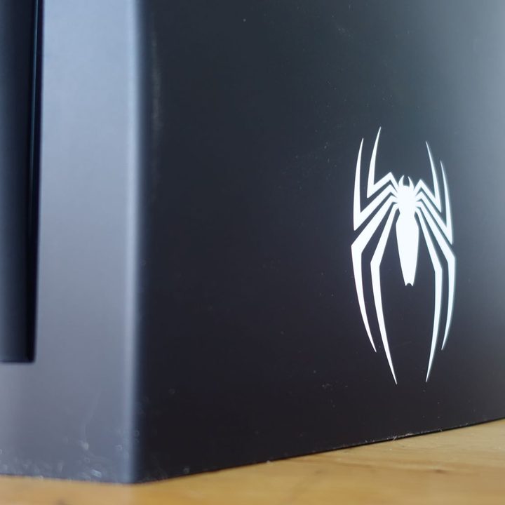 A Spider-Man logo appears on the back of a PS5.