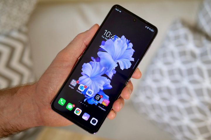A person holding the Tecno Phantom V Flip, showing the main screen.