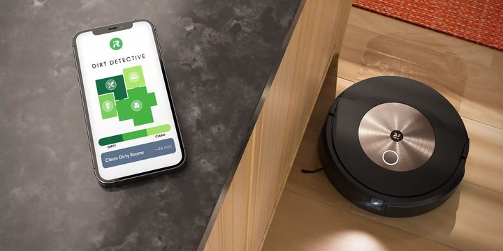 The Combo j9+ cleaning near a couch with a smartphone on it.
