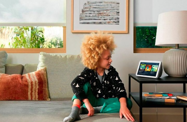 A kid sits on the couch and looks at the Amazon Echo Show (2nd Gen).