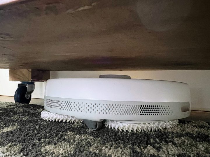A Narwal robot stuck beneath a home entertainment center.