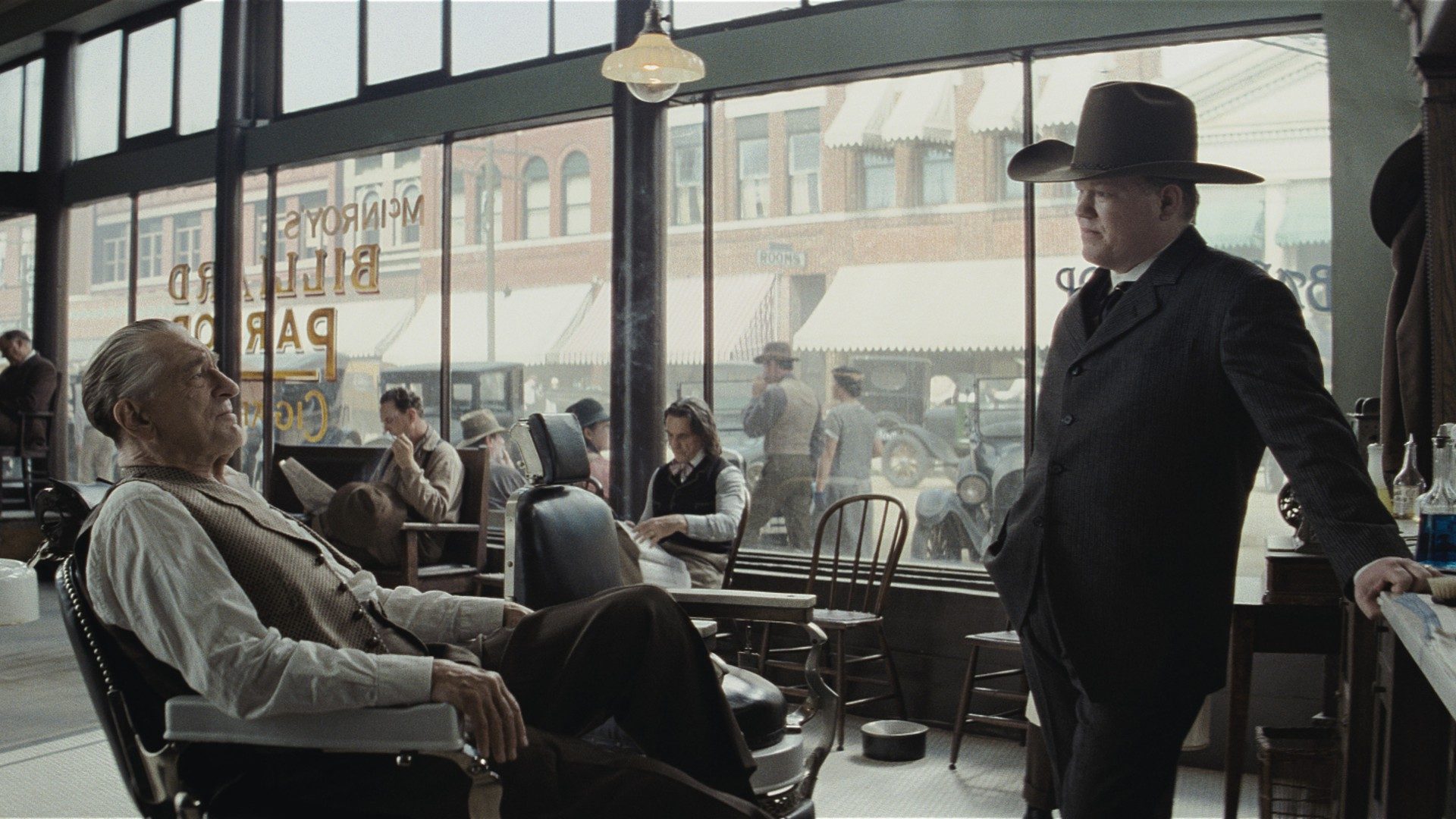 Robert De Niro sits in a barber chair and talks to Jesse Plemons standing over him