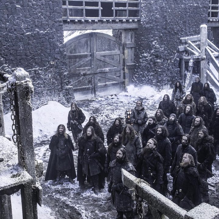 A man stands on a perch while looking over men in a courtyard.