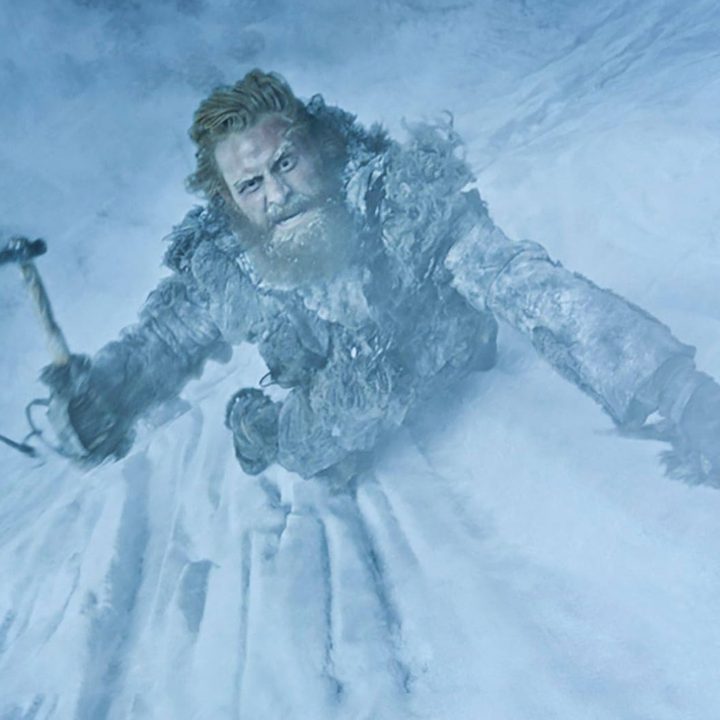 A man scales an ice wall with a pick in Game of Thrones.