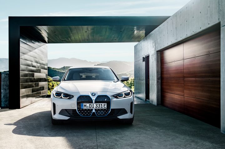 A BMW i4 parks in front of a modern building.