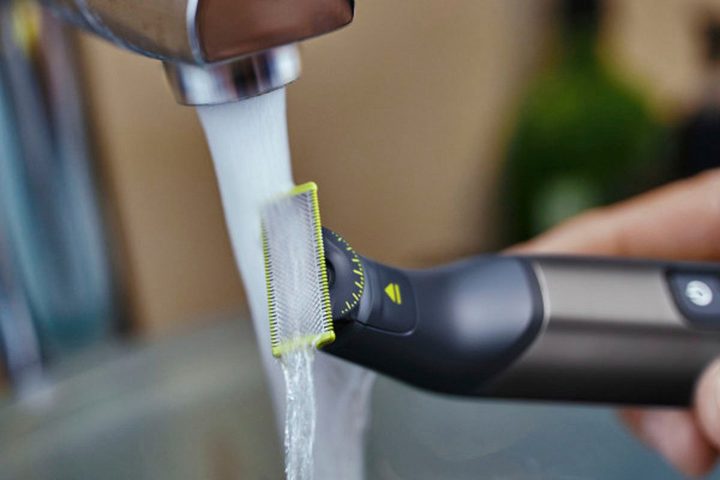 Philips Norelco OneBlade 360 being washed under a faucet