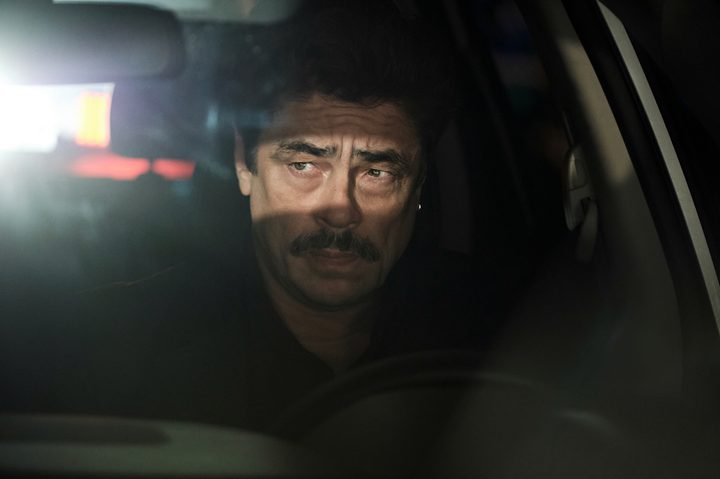 Benecio del Toro stares while sitting in the front seat of his car in Reptile.