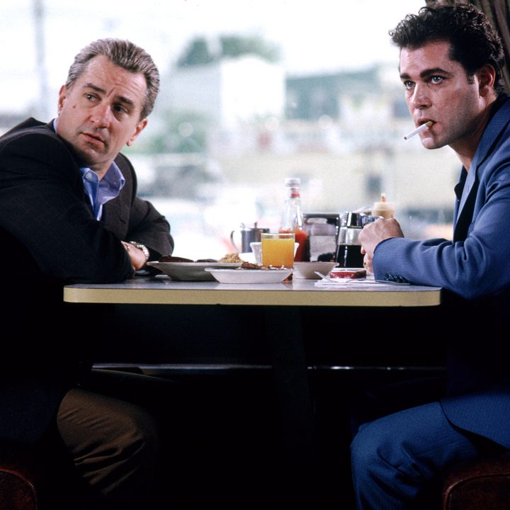 Two men sit at a diner table and stare.